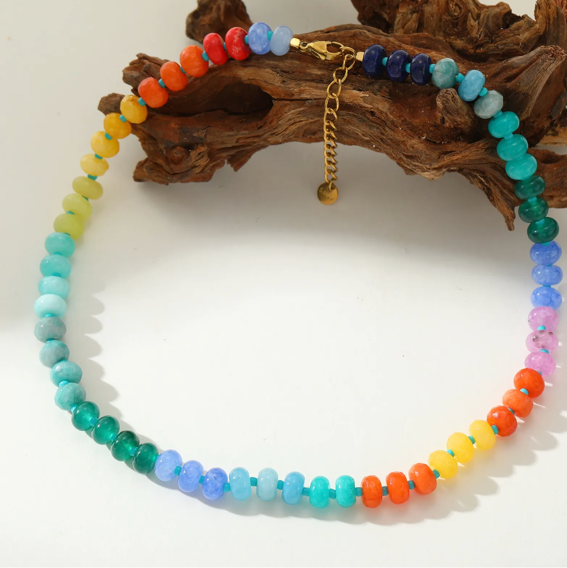 Colorful beaded necklace on a white background with a wooden log