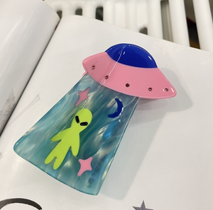 Colorful alien-themed phone case with pink UFO design on a white surface
