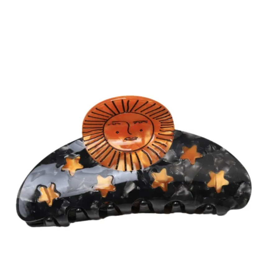 Decorative hair clip with sun and star design on a white background