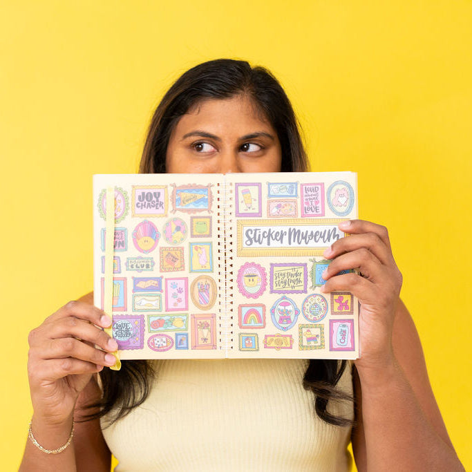Woman holding a sticker book with colorful stickers against a yellow background