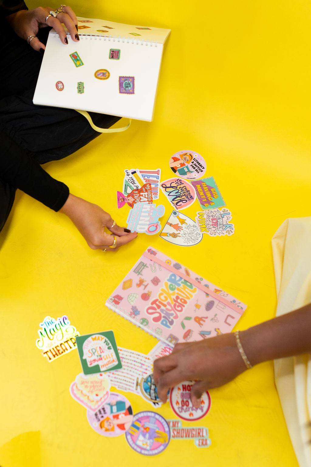 Two people interacting with colorful stickers on a yellow surface