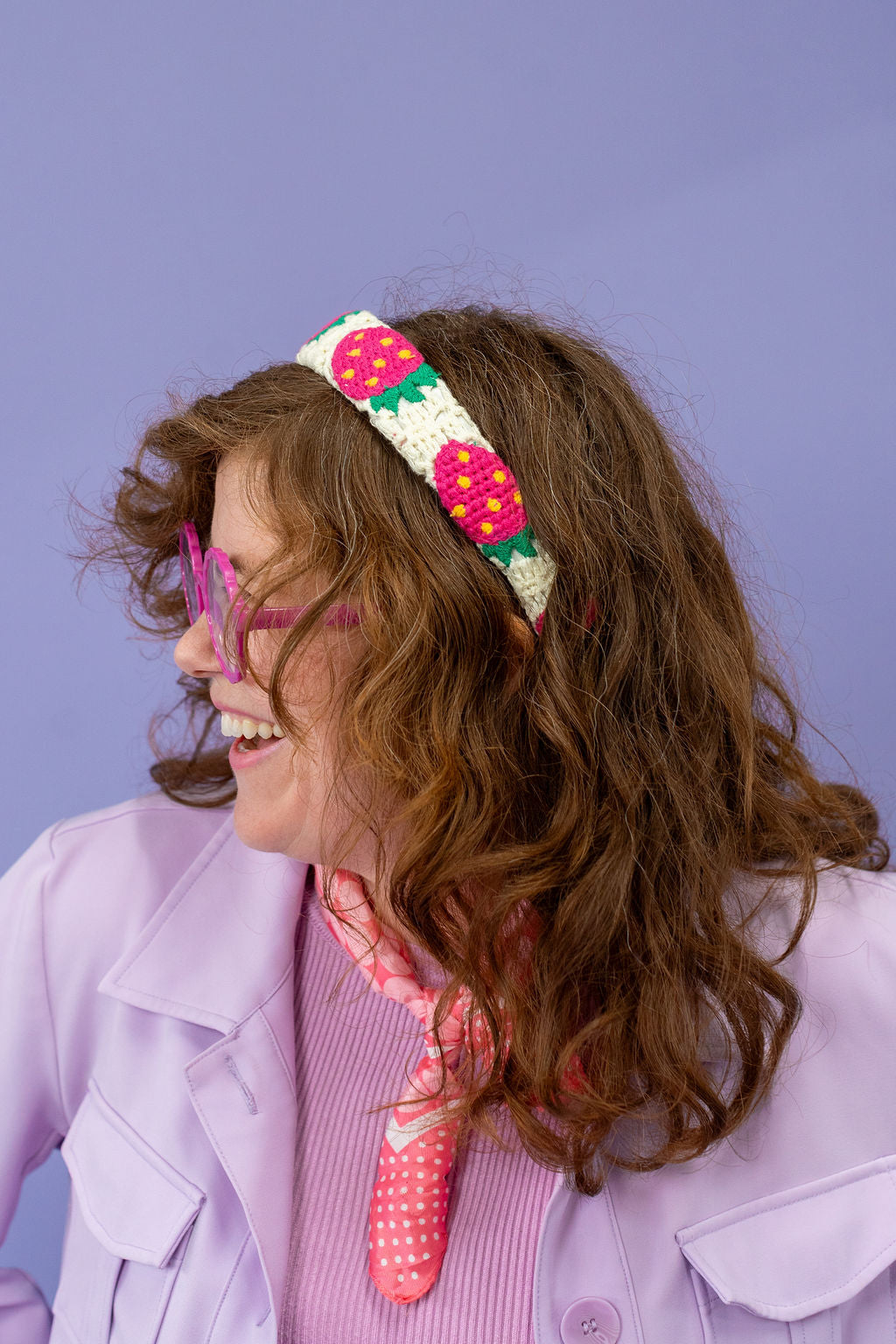 Person wearing a colorful headband with strawberry design against a purple background