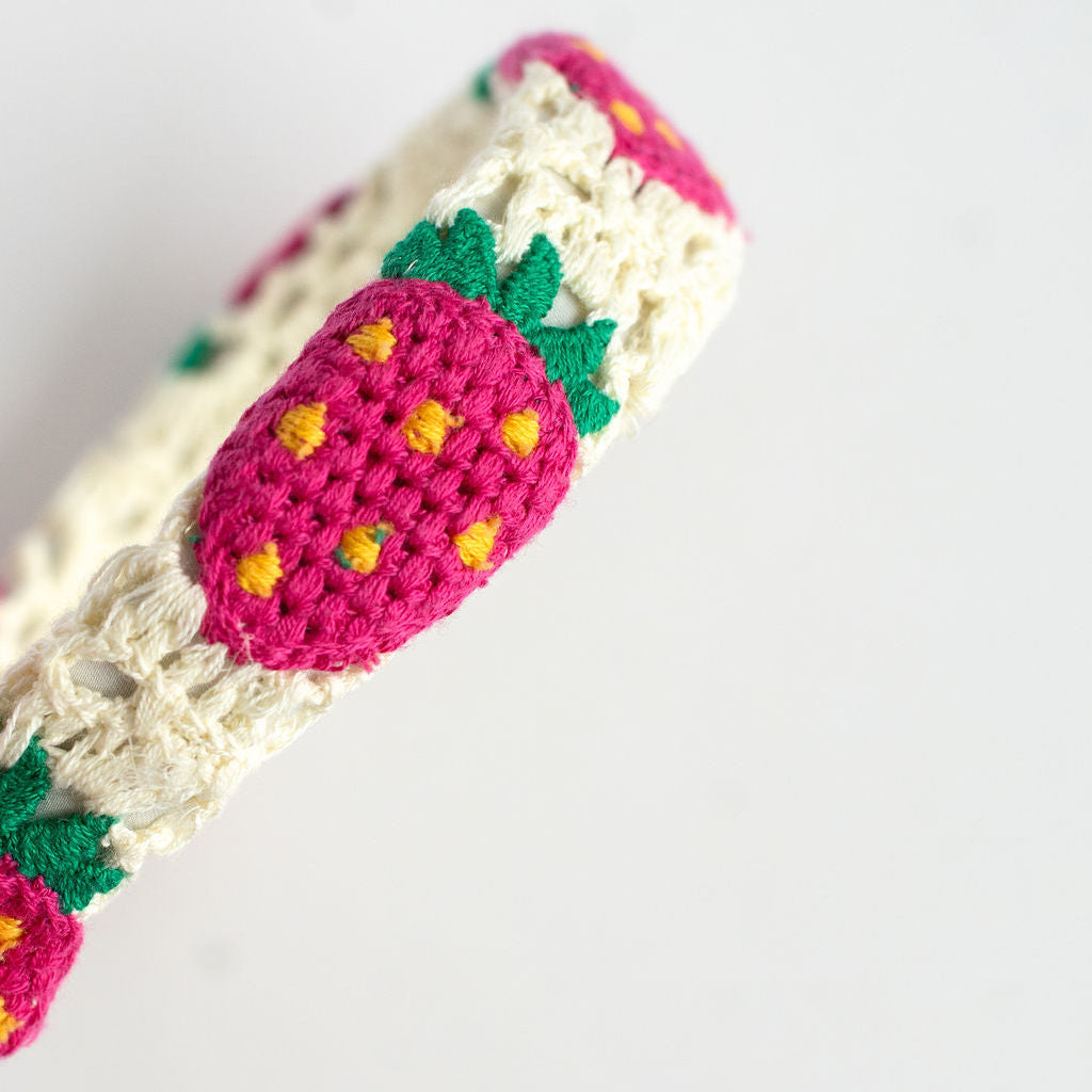 Crocheted headband with strawberry pattern on a white background