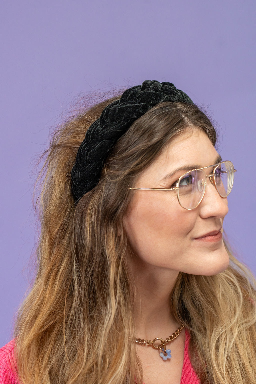 Woman wearing a black headband with braided design against a purple background