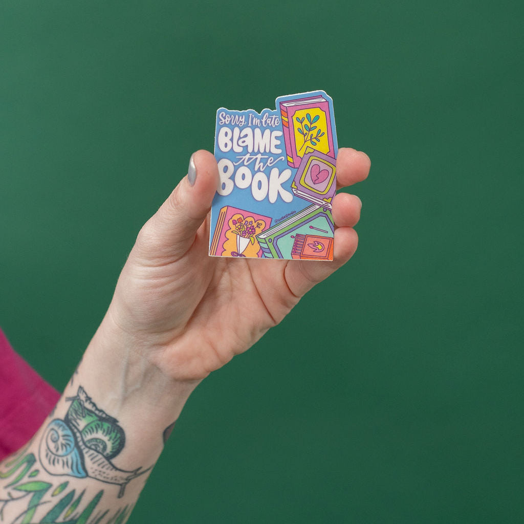 Hand holding a colorful sticker against a green background