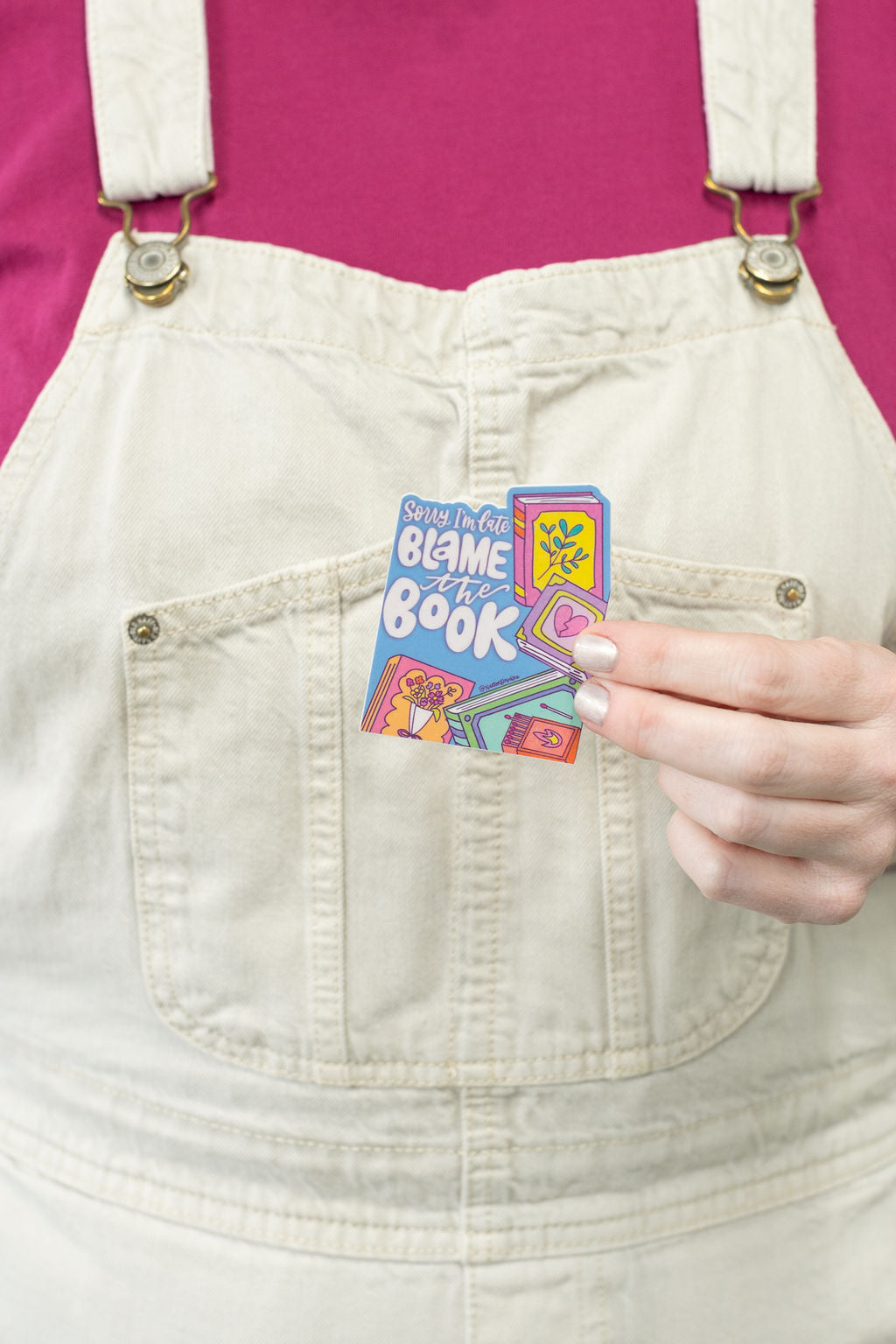 Person holding a colorful stickers against white overalls