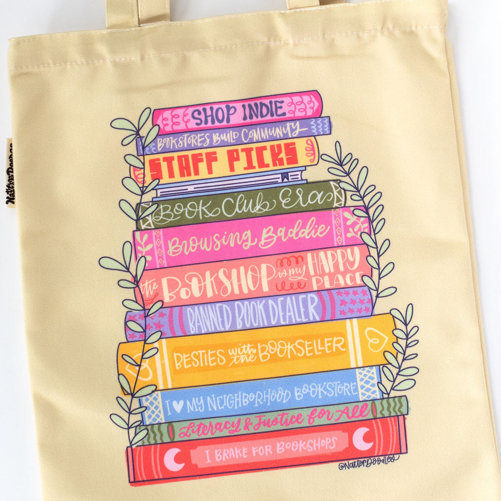 yellow tote bag with colorful book stack design on a white background