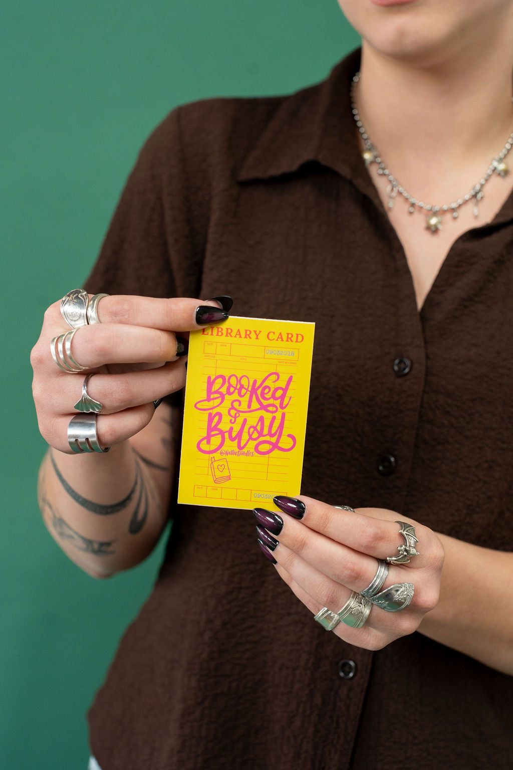 Person holding a yellow sticker with pink text against a green background