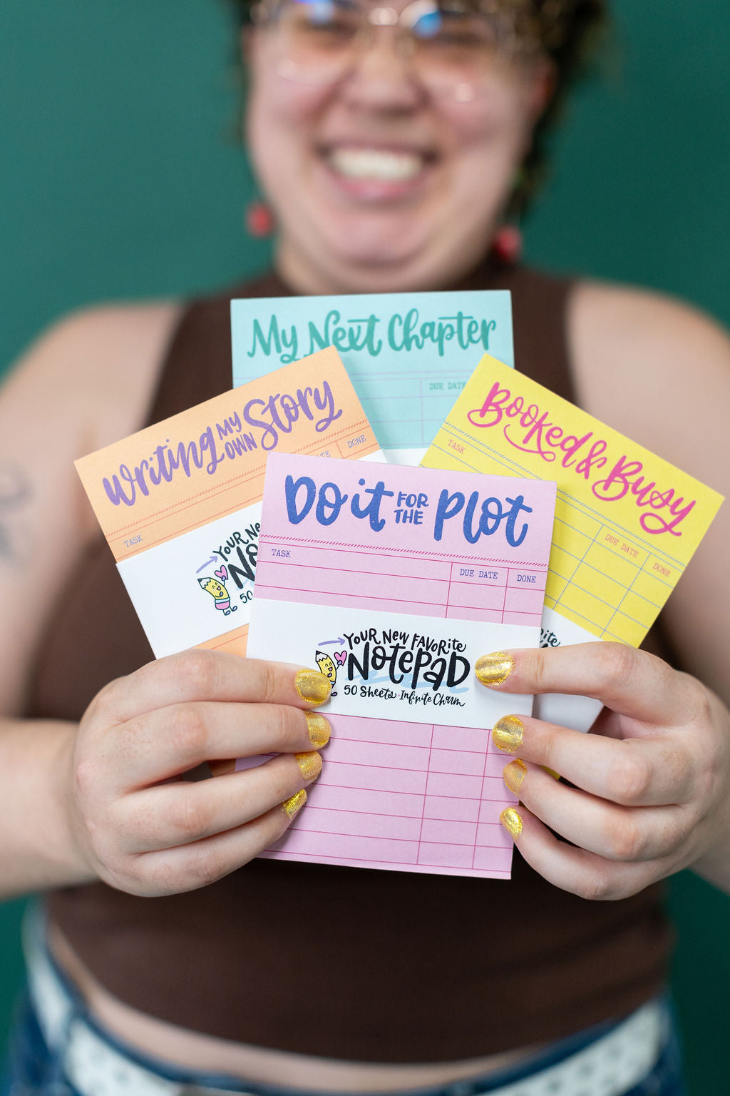 Person holding a variety of colorful notepads with different designs and text.
