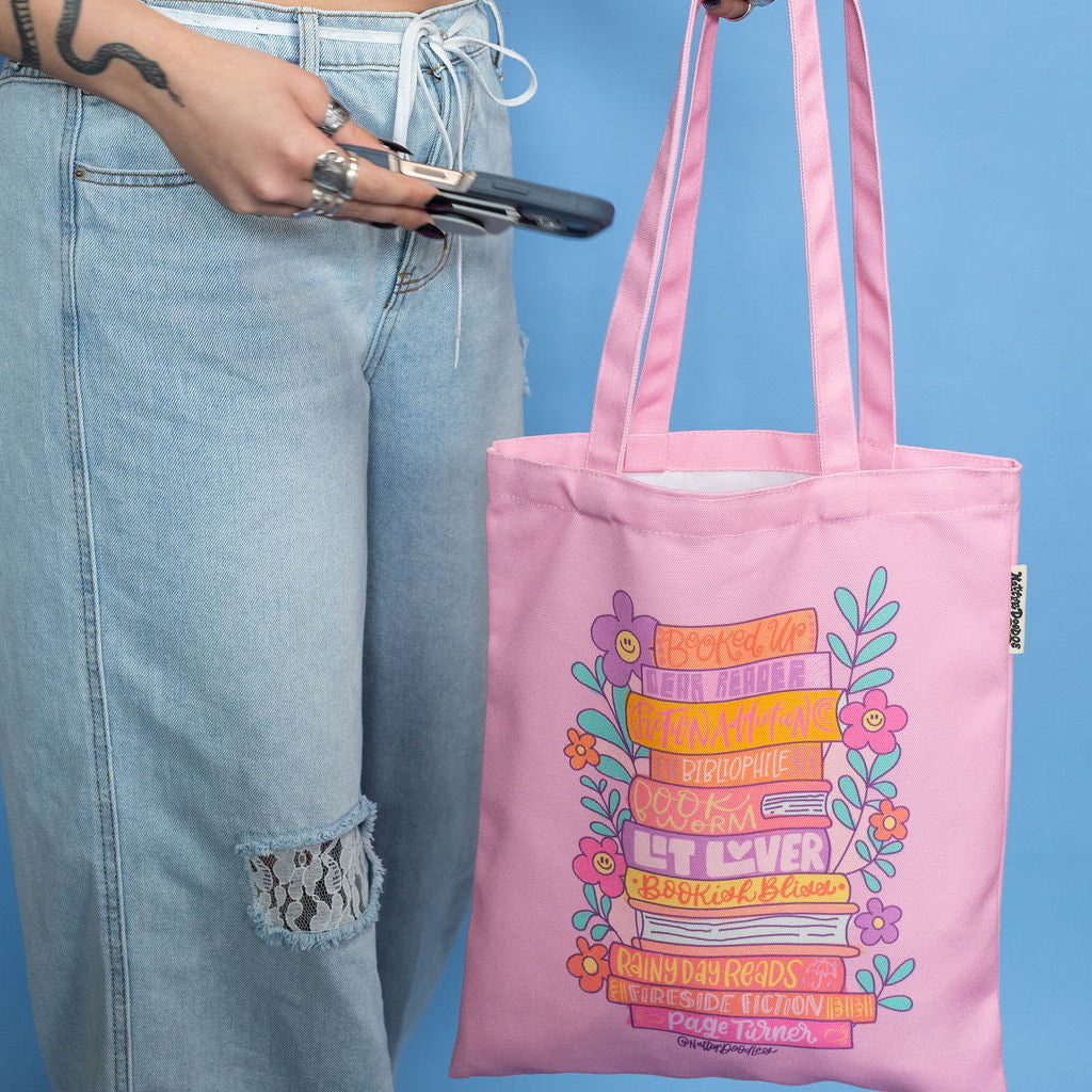 Person holding a pink tote bag with colorful design against a blue background