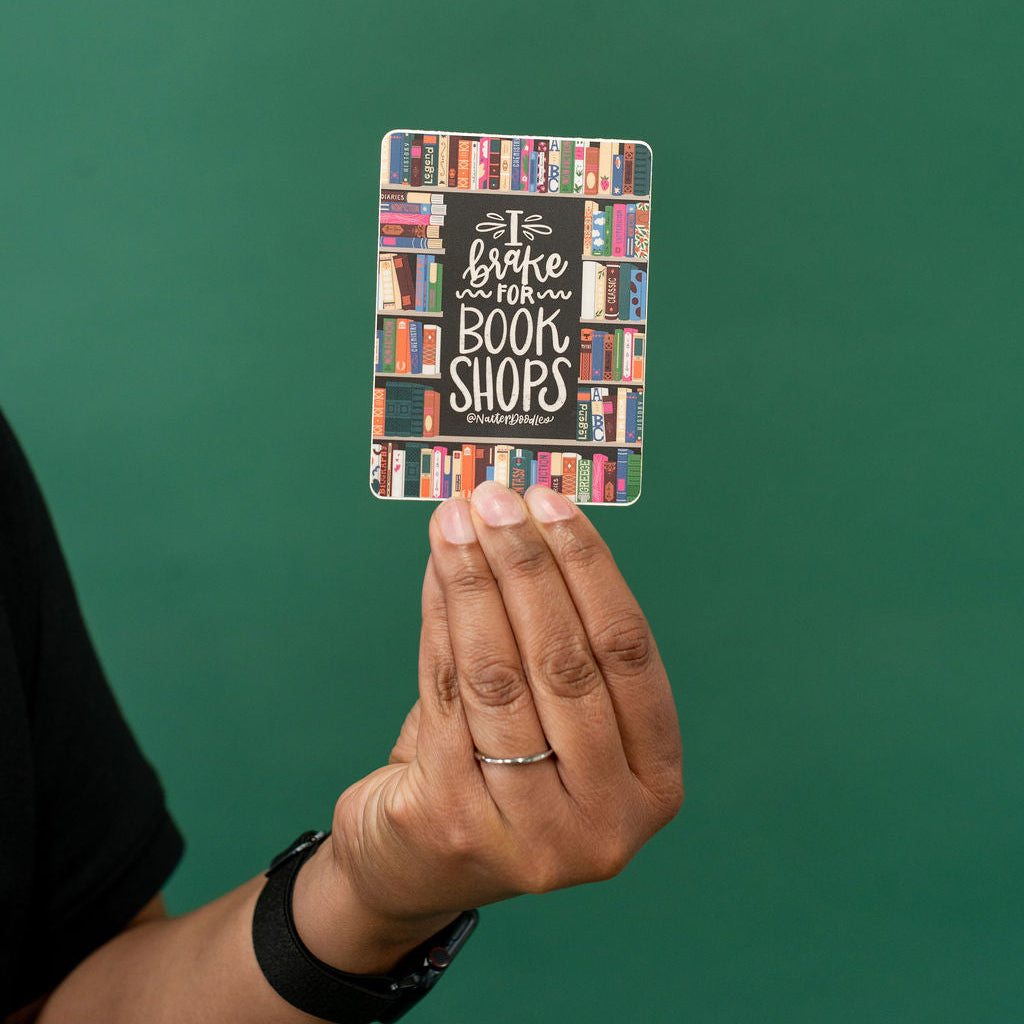 Hand holding a card with bookshelf design against a green background