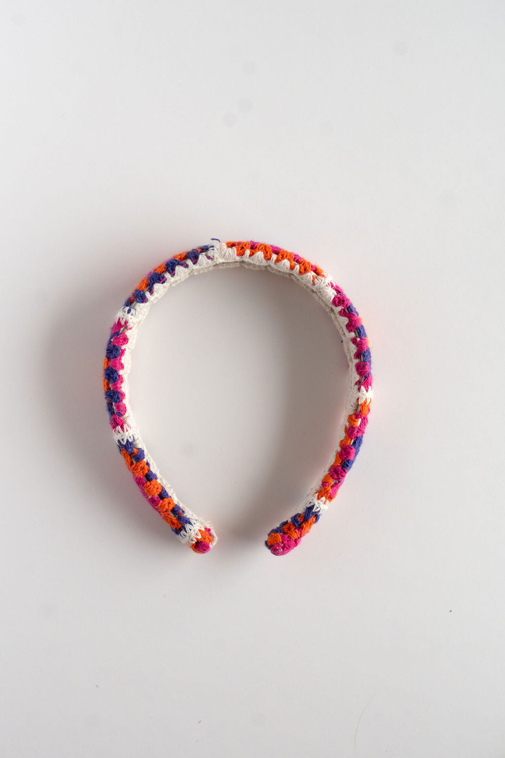 Colorful crochet headband on a light gray background