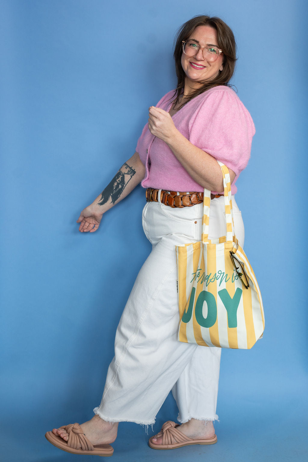 Woman holding a yellow and green tote bag with text against a blue background