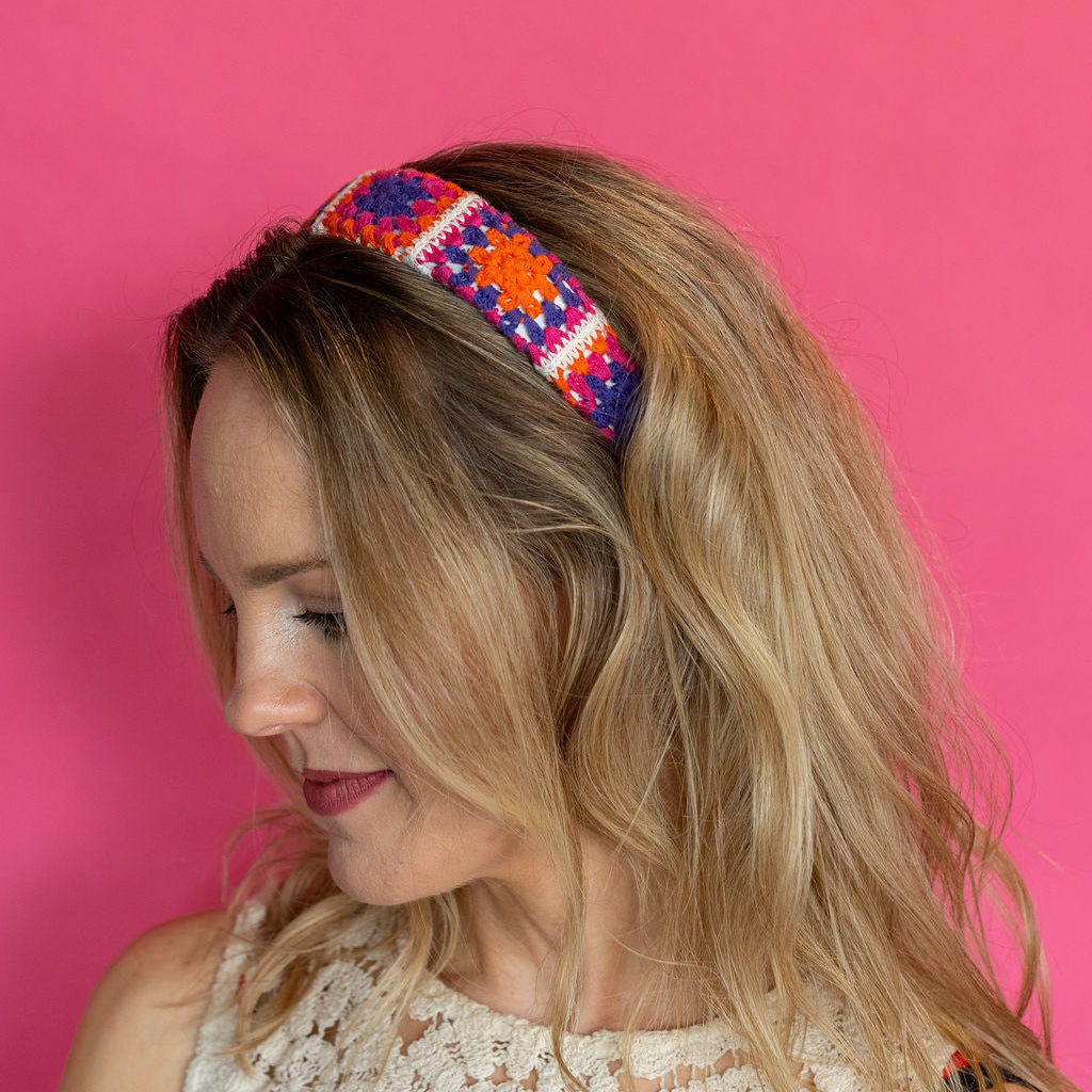 Woman wearing a colorful headband against a pink background