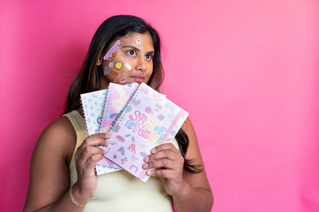 Woman holding colorful greeting cards against a pink background