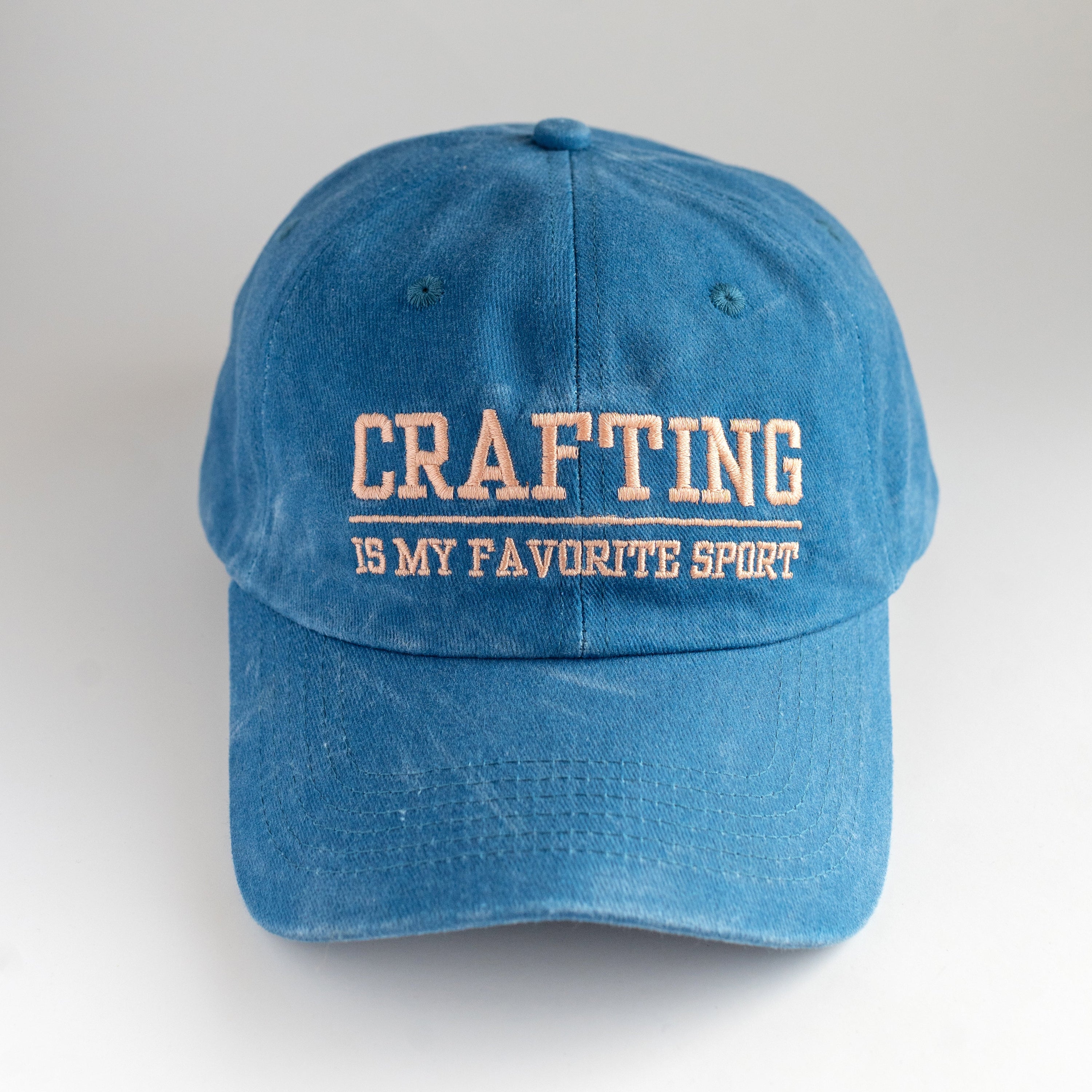 Blue cap with 'Crafting is my favorite sport' text on a white background