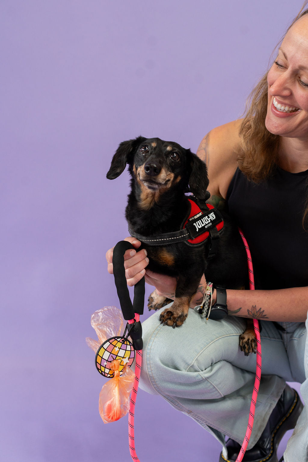 Woman holding a small dog with a purple background