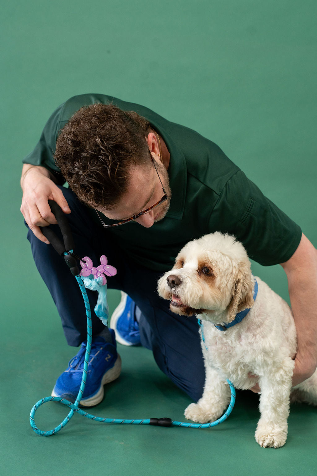 Man kneeling with a dog on a green background
