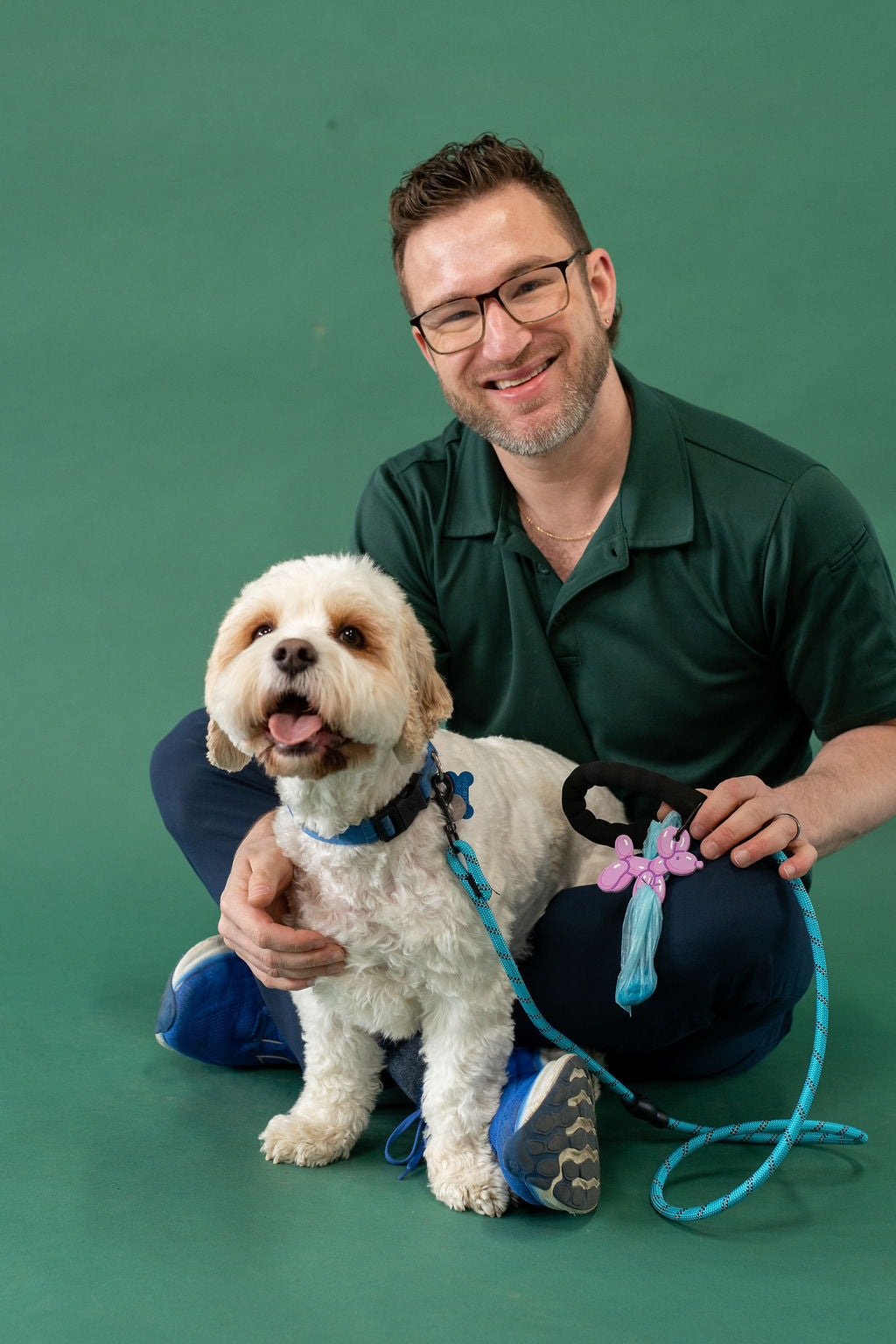 Man in a green shirt with a small white dog on a green background