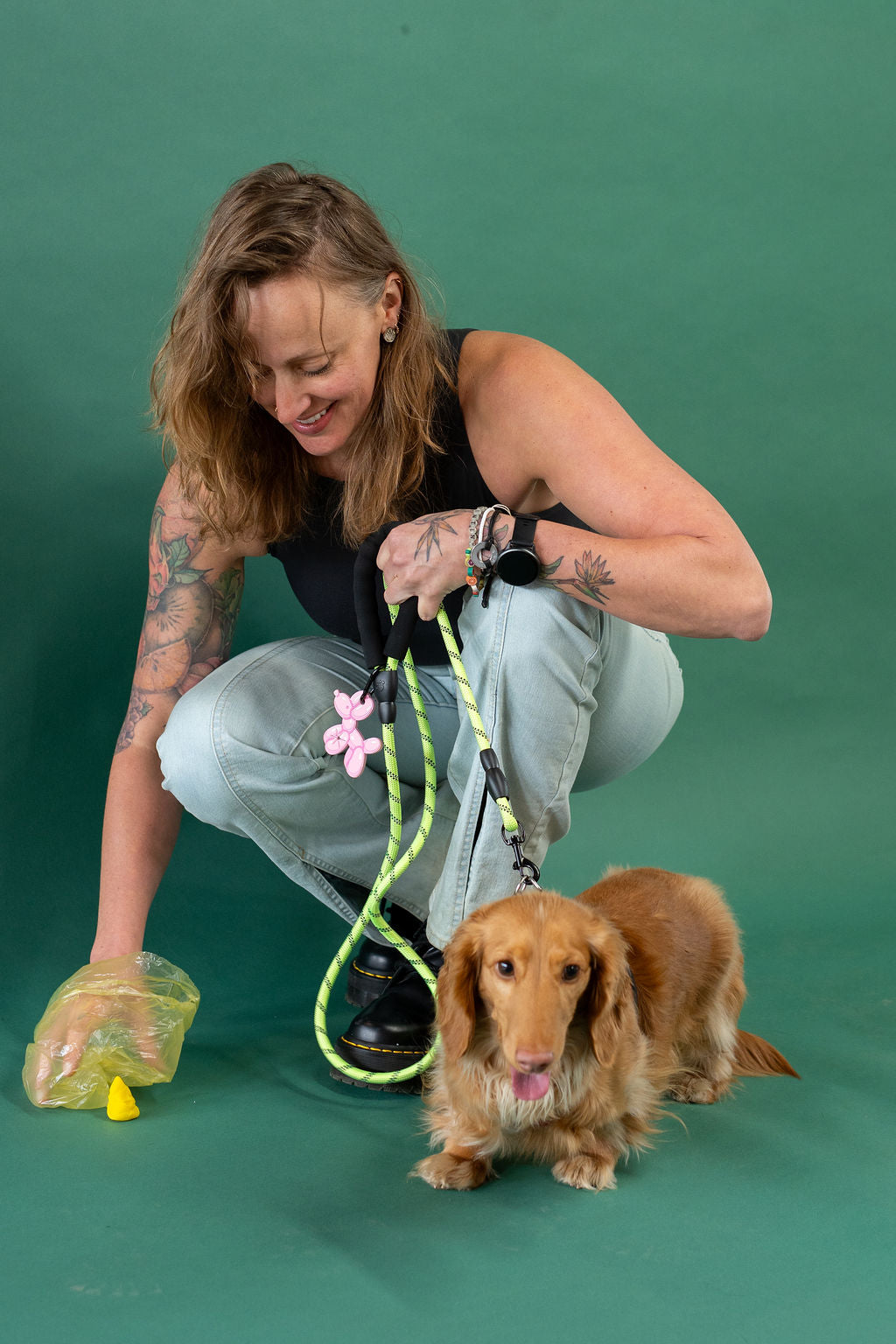 Woman with tattoos and a dog on a green background