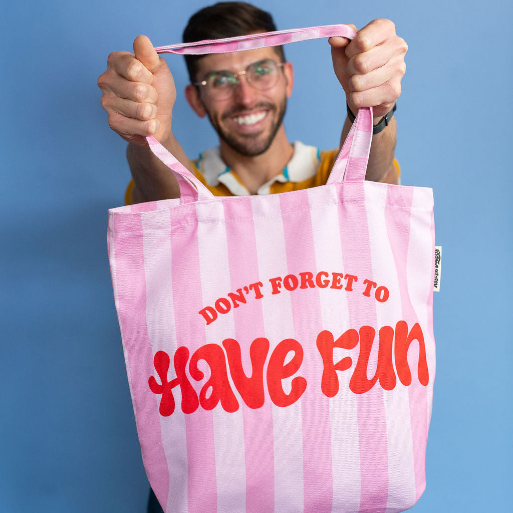 Person holding a pink and white striped tote bag with text against a blue background