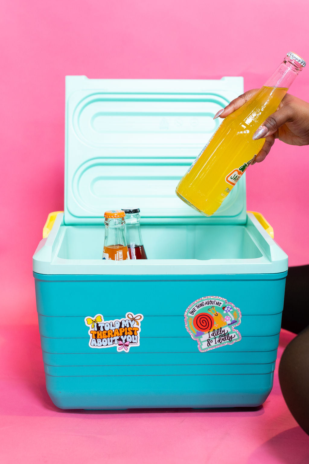 Turquoise cooler with colorful stickers on a pink background