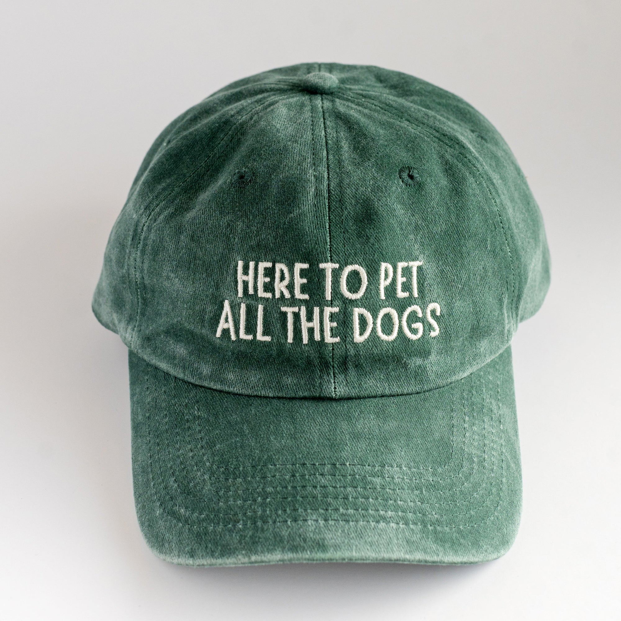 Green cap with 'Here to pet all the dogs' text on a white background