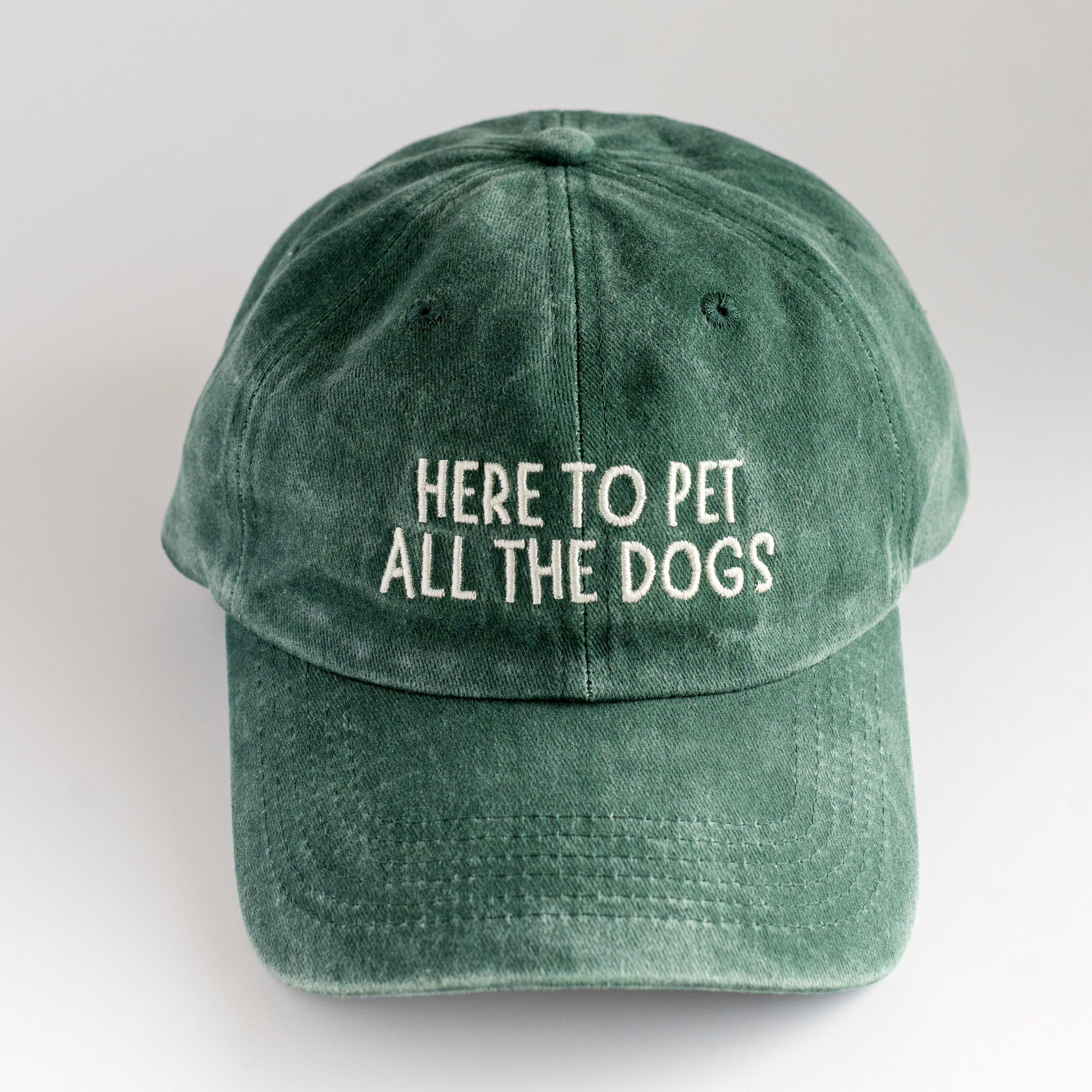 Green cap with 'Here to pet all the dogs' text on a white background