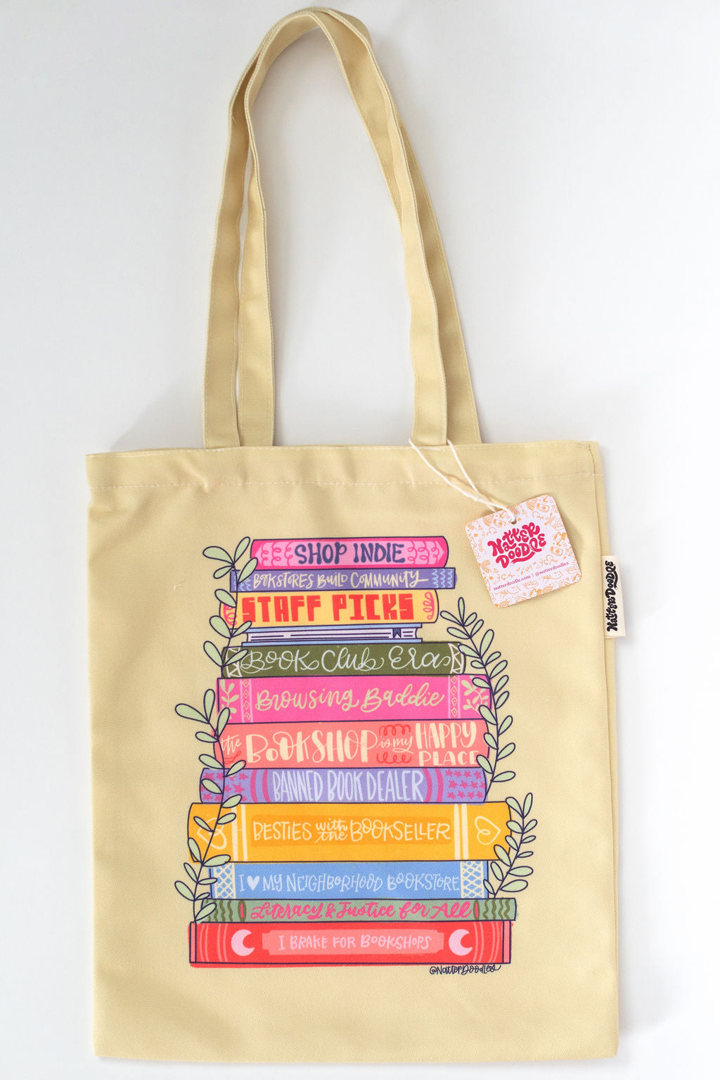 yellow tote bag with colorful book-themed design on a white background