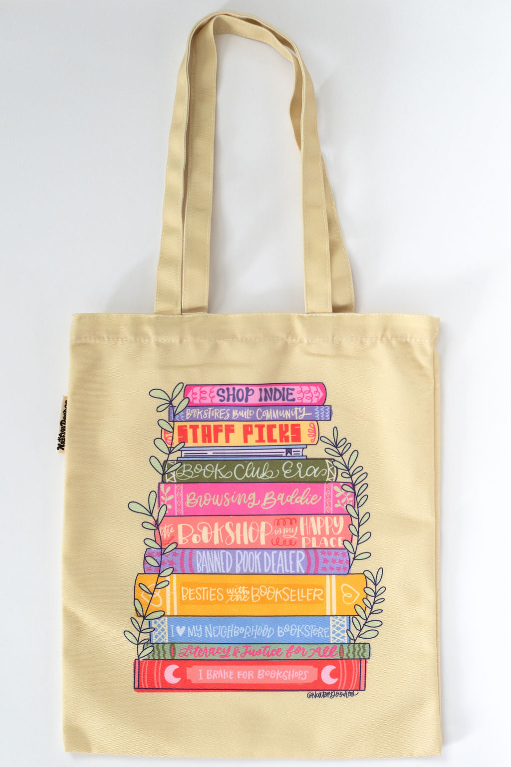 yellow tote bag with colorful book stack design on a white background