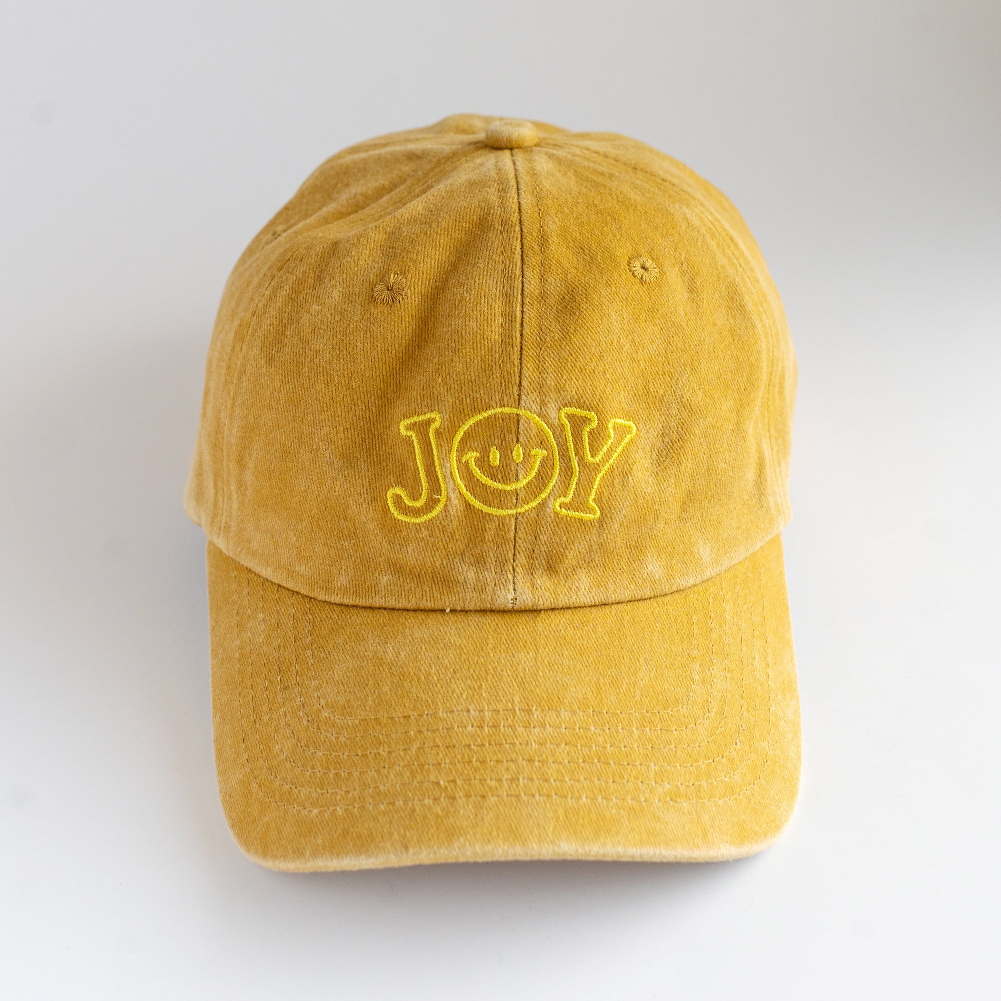 Yellow cap with 'JOY' embroidery on a light gray background