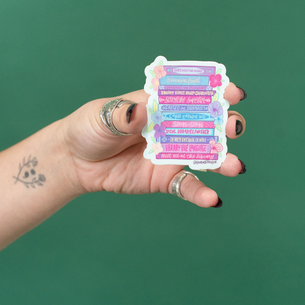 Hand holding a colorful sticker with text against a green background