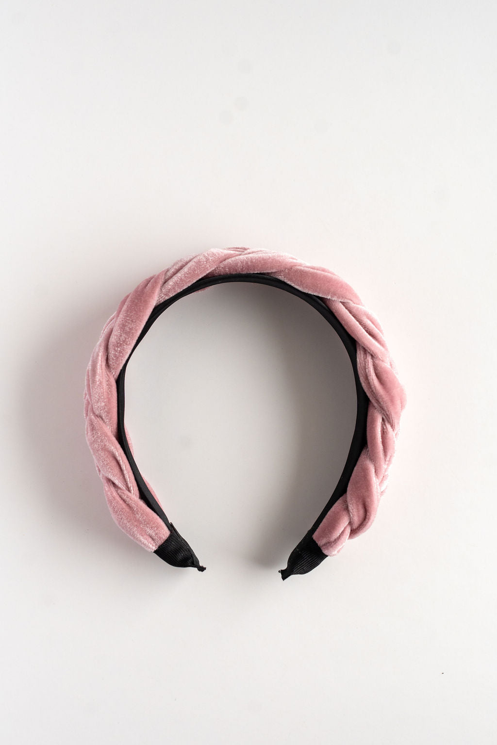 Pink velvet headband with black accents on a light gray background