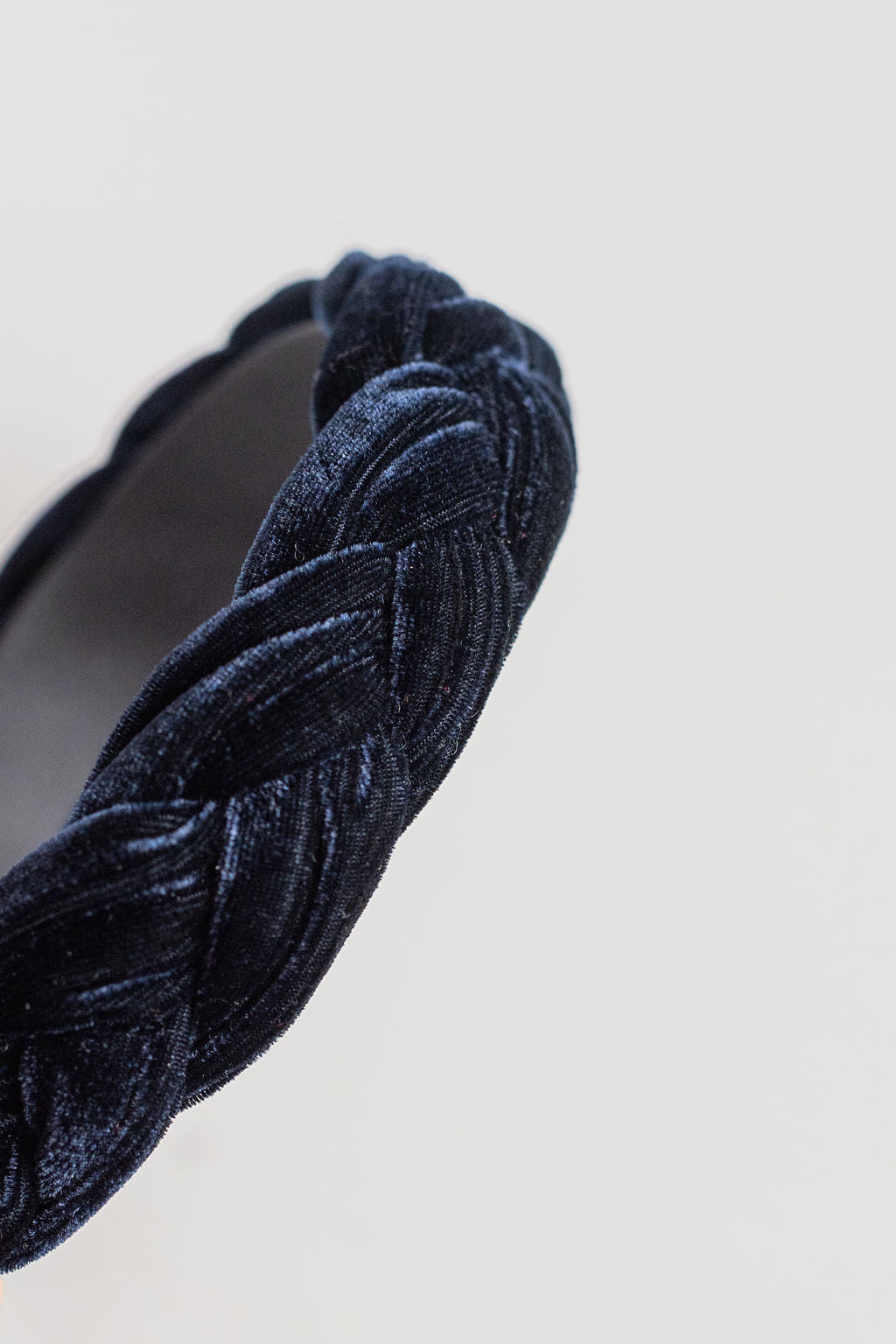 Navy blue velvet headband with braided design on a light gray background