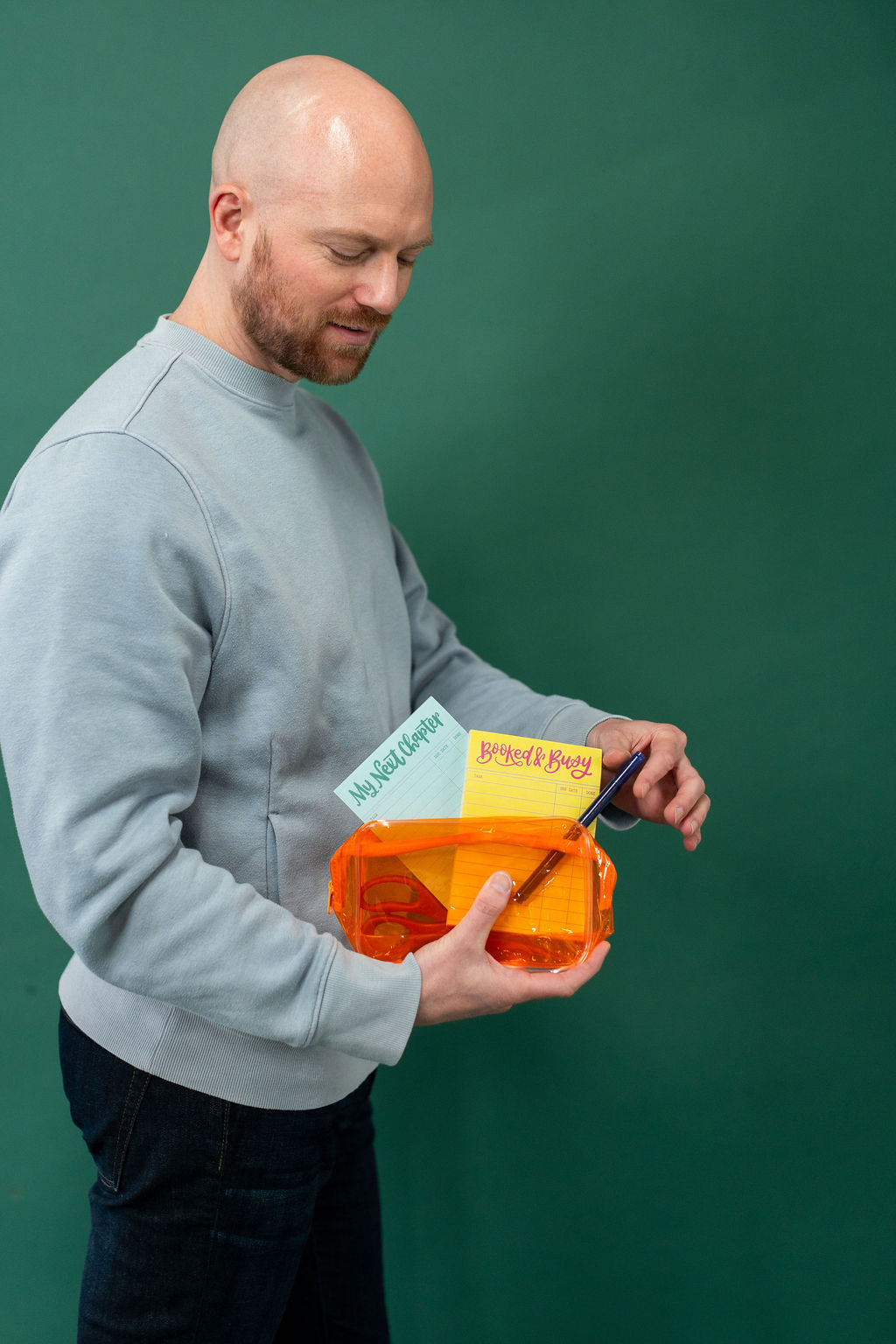 Man holding a small orange container with a green background