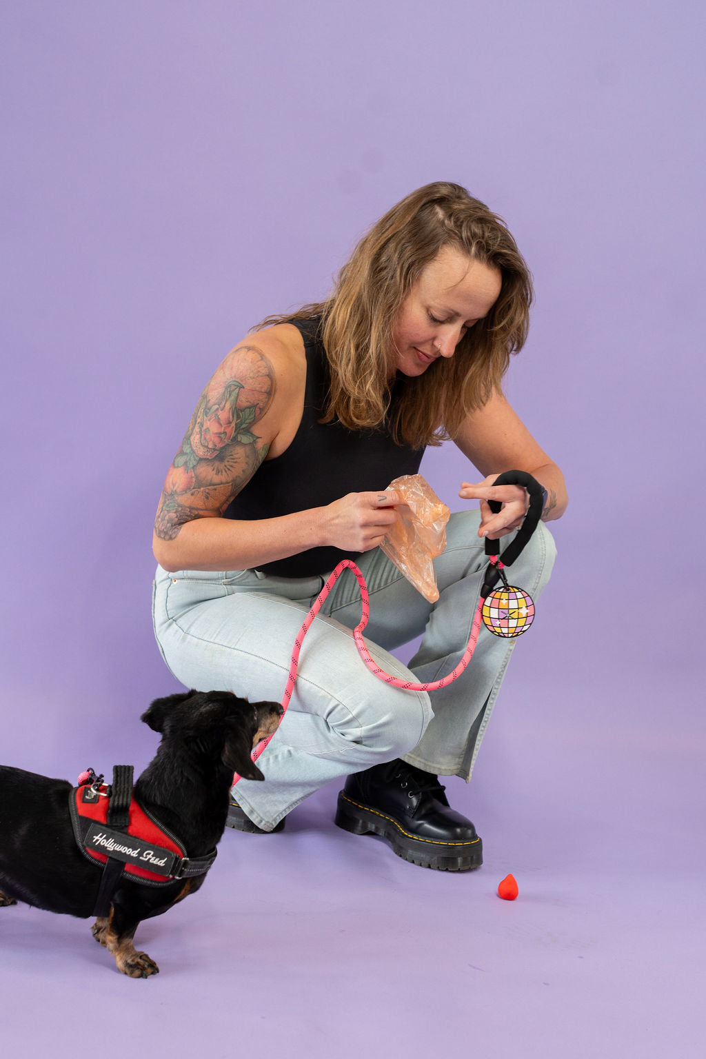 Woman with tattoos interacting with a dog on a purple background