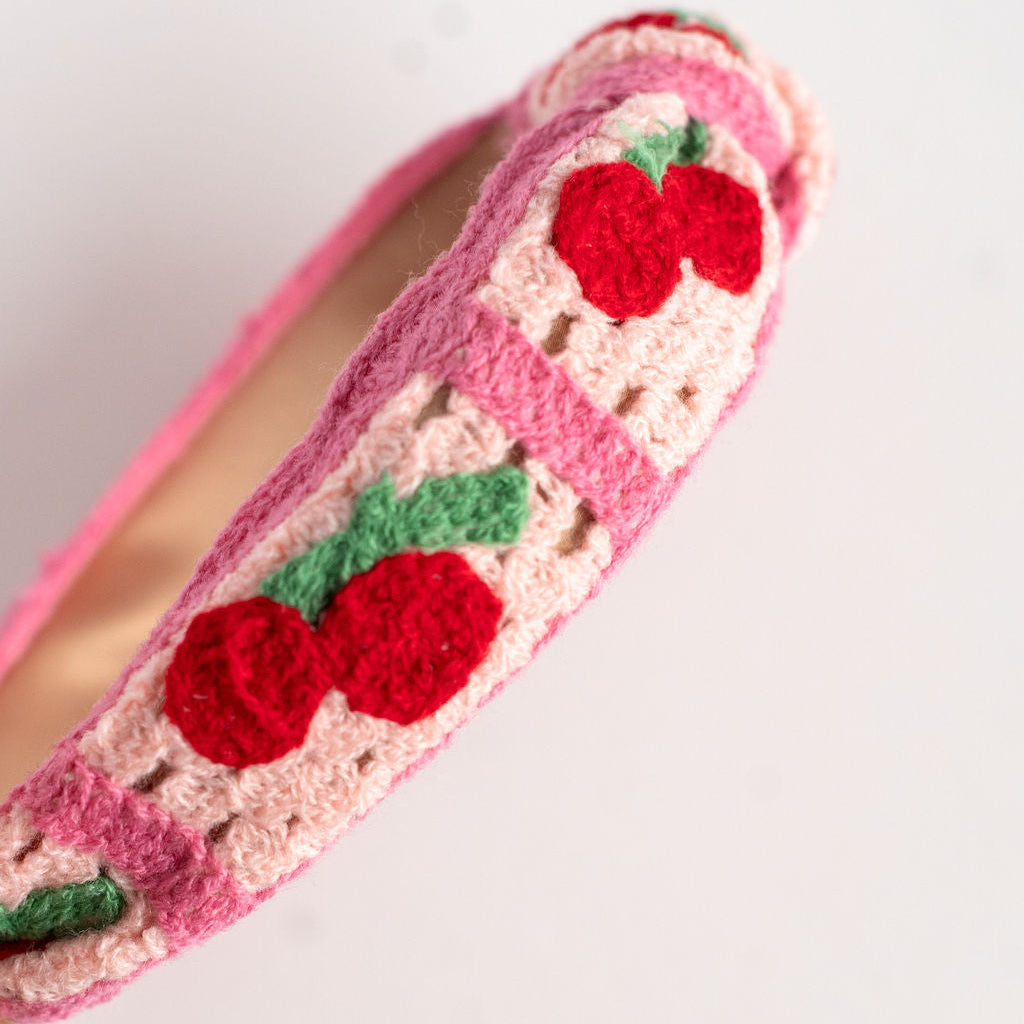 Pink headband with red cherry designs on a white background