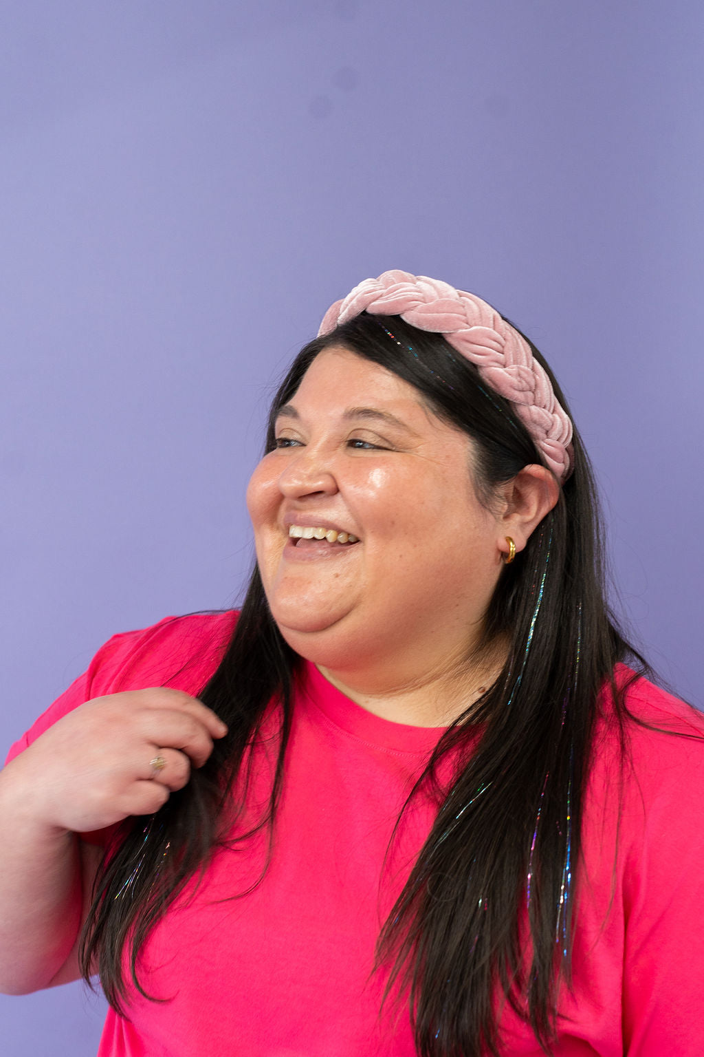 Woman wearing a pink shirt and headband against a purple background