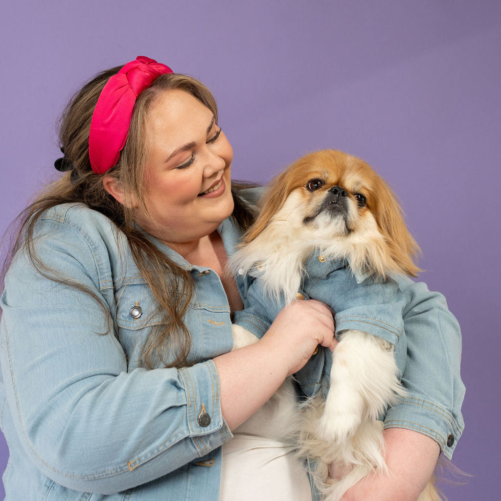 Woman holding a small dog against a purple background