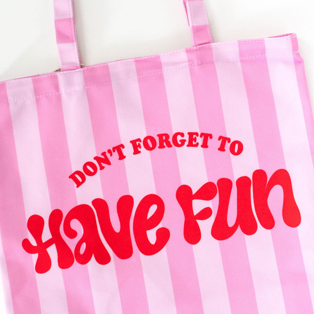Pink and white striped tote bag with red text 'DON'T FORGET TO HAVE FUN' on a white background