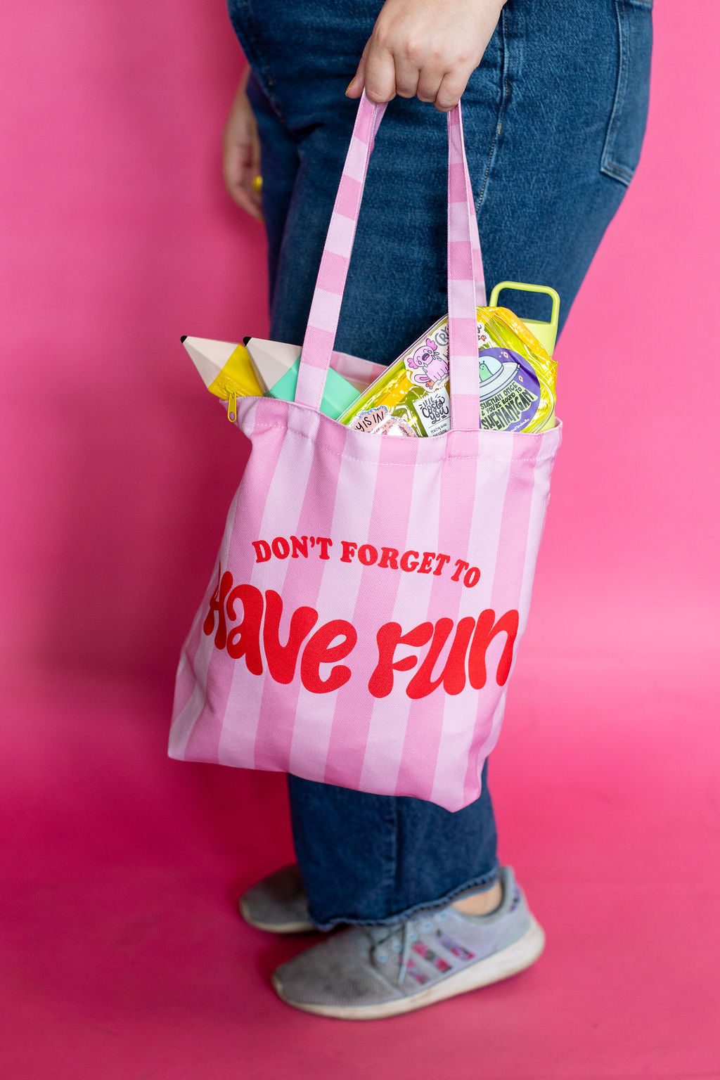 Person holding a pink checkered tote bag with text against a pink background