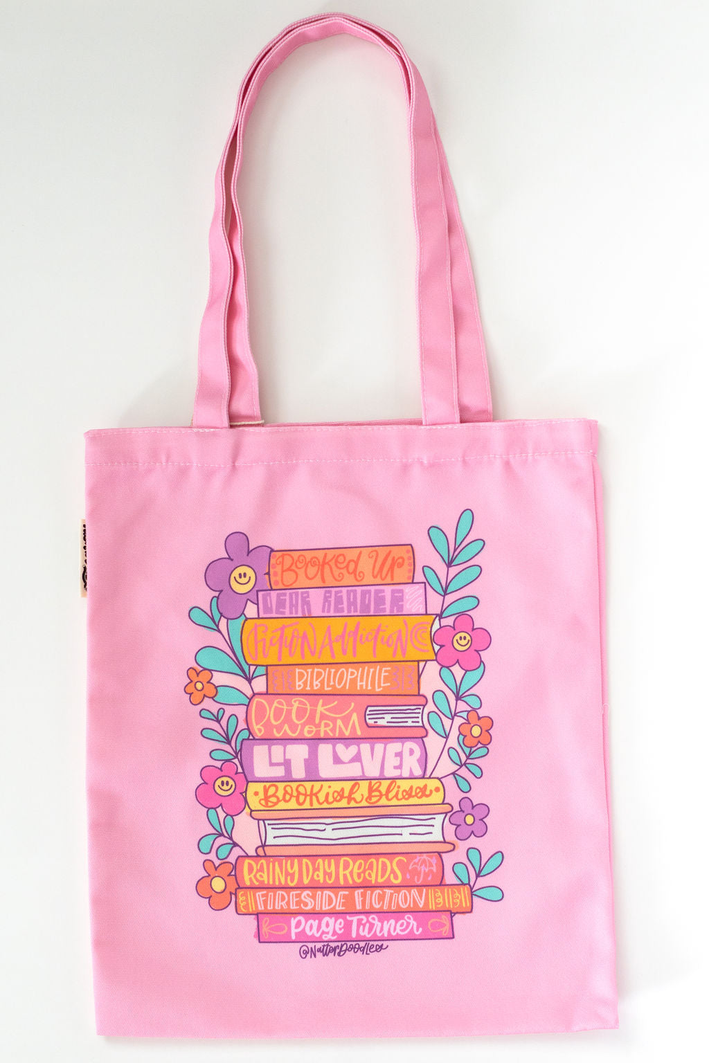 Pink tote bag with colorful text and floral design on a white background