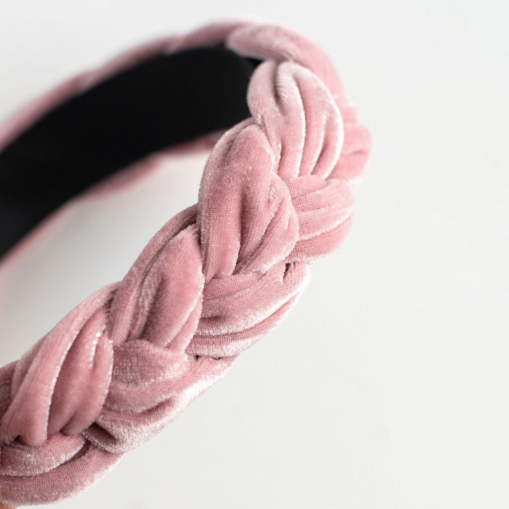 Pink velvet headband with braided design on a white background