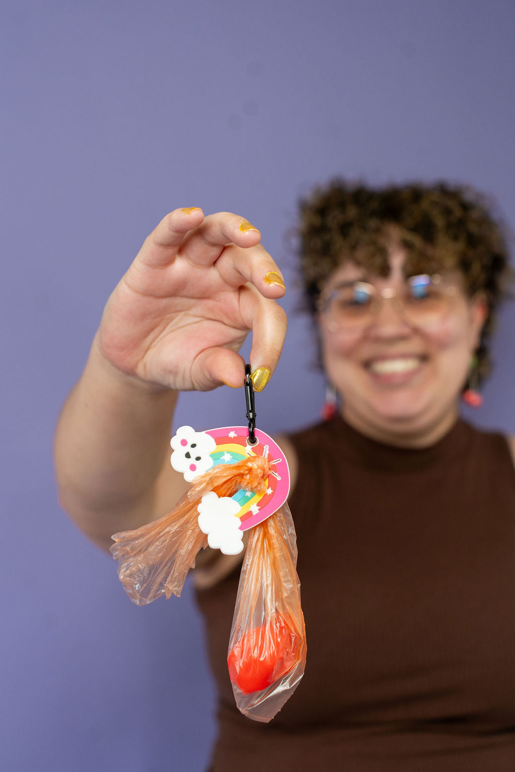 Person holding a decorative poo pal against a purple background