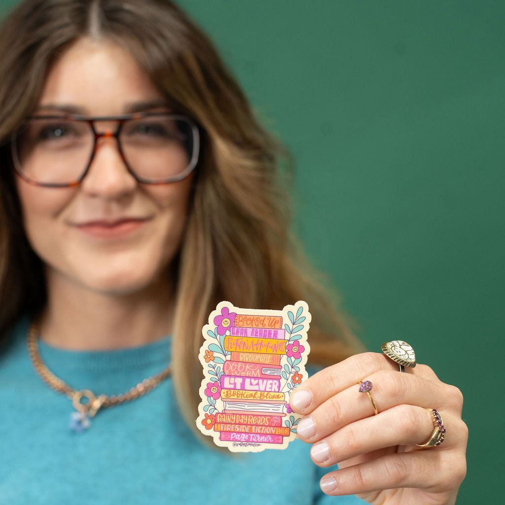 Woman holding a colorful sticker with text against a green background