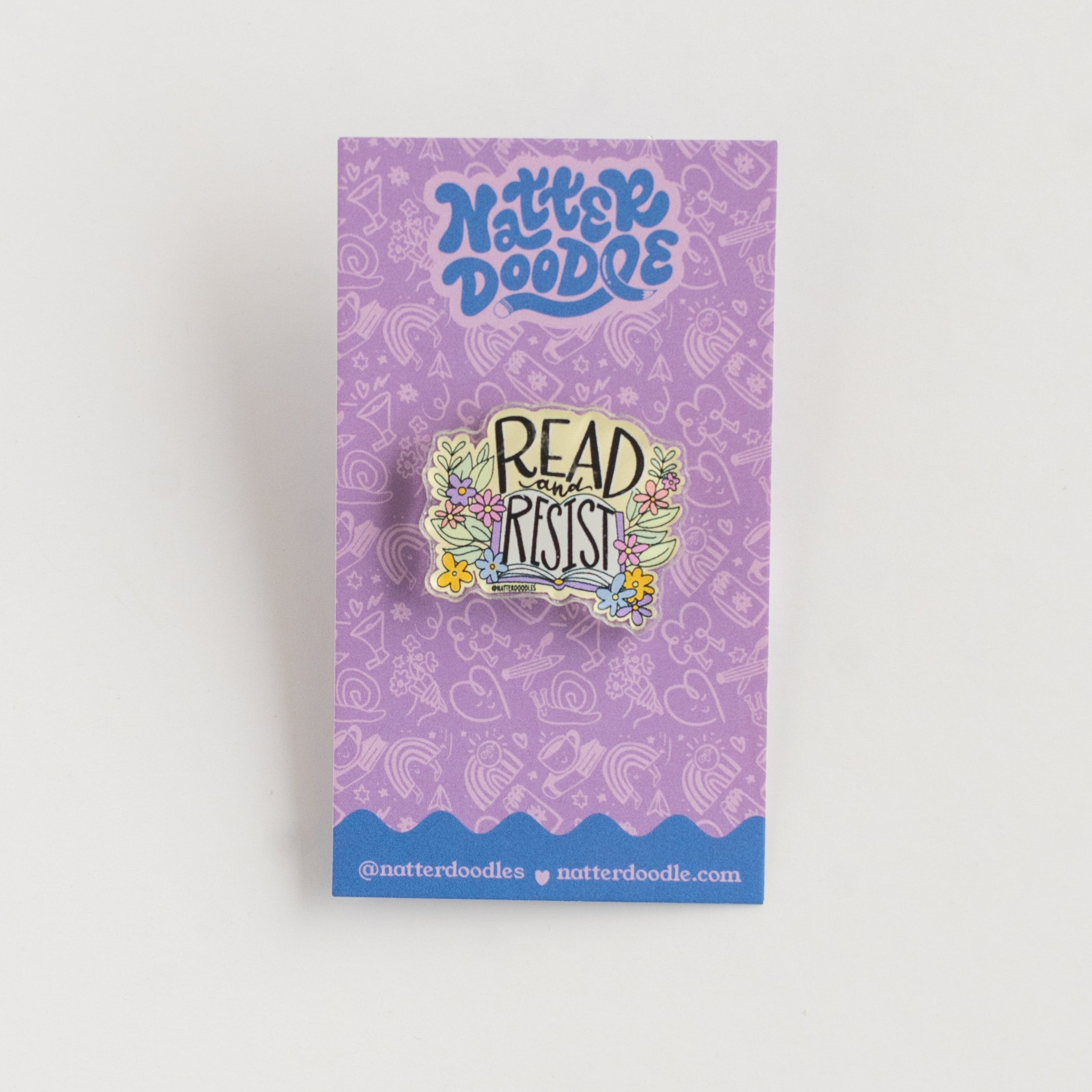 Pin with 'Read and Resist' text on a purple card with 'NatterDoodle' branding.