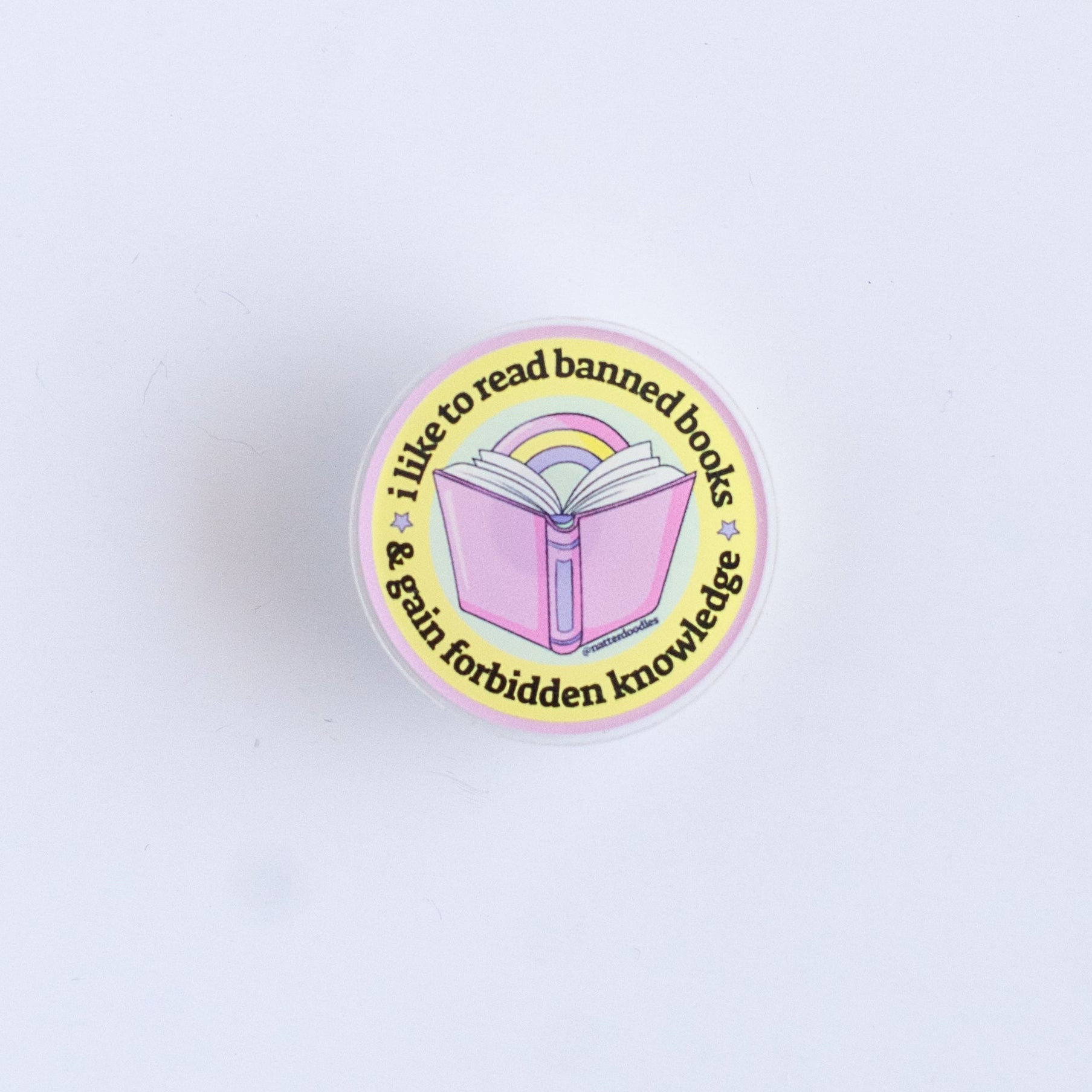 Pin with a rainbow book design on a light purple background