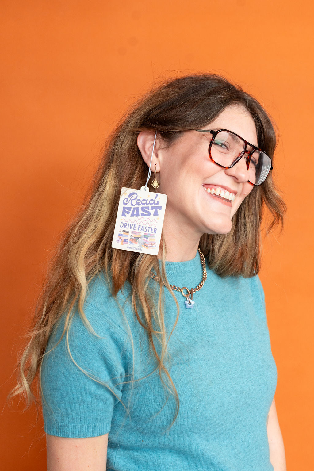 Woman wearing glasses with a visible air freshener orange background