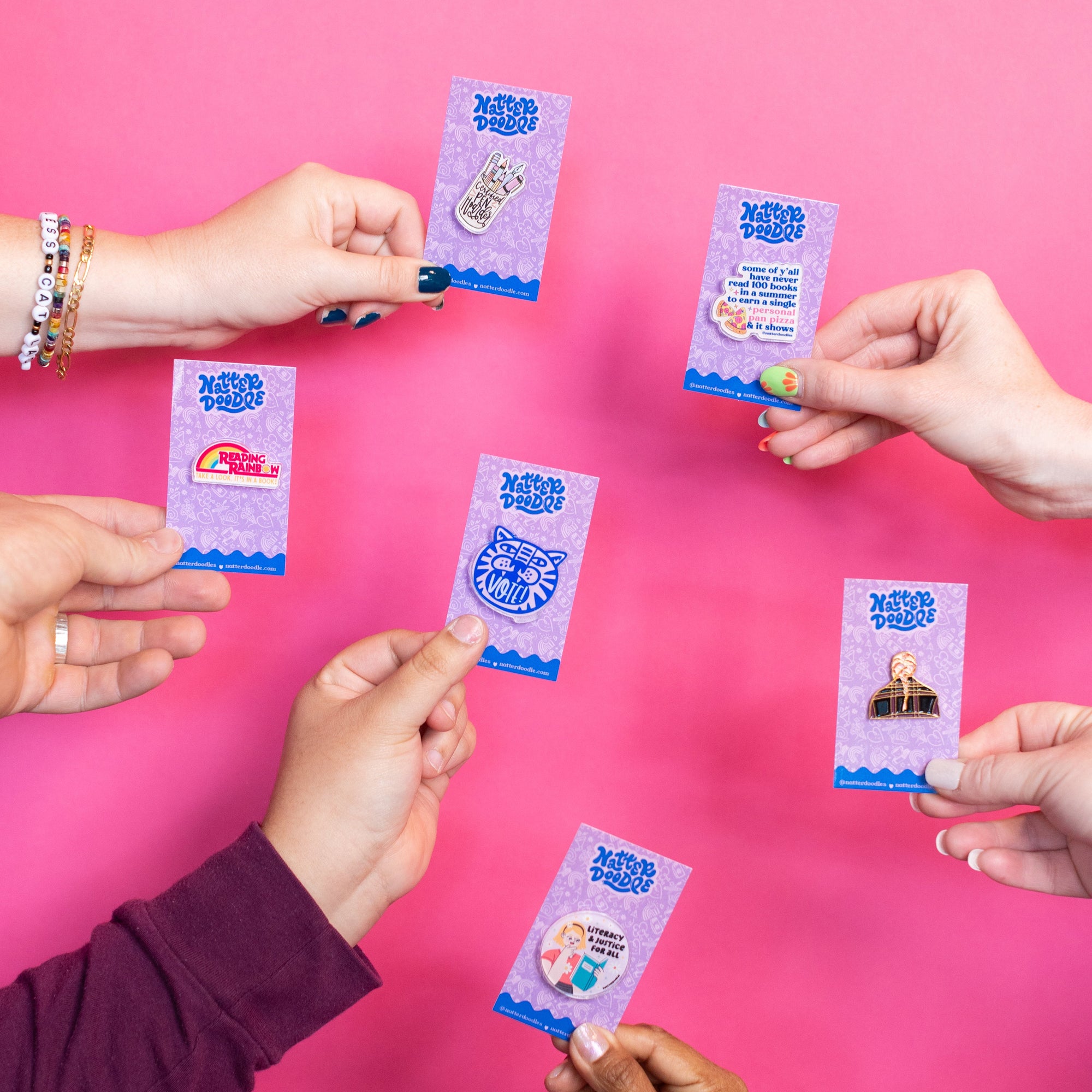 Hands holding colorful cards against a pink background
