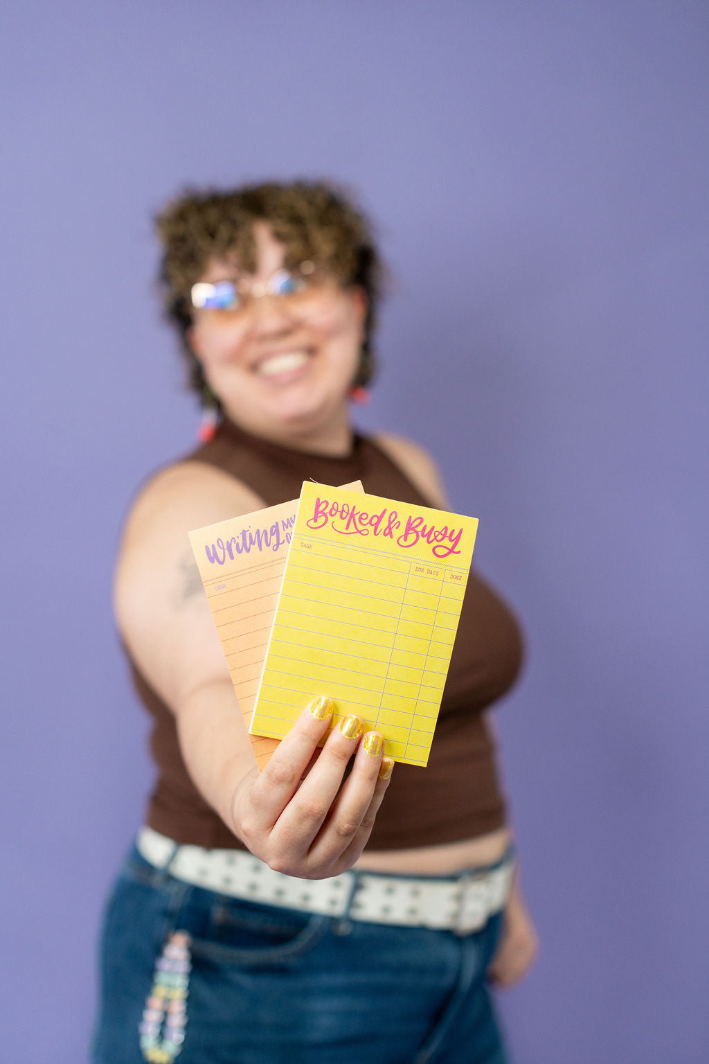 Person holding two yellow notepads with text against a purple background